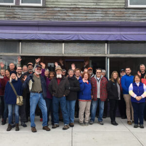 People celebrating in front of the historic Parker J. Noyes building in Lancater NH before renovation began