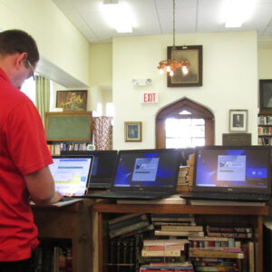 a man installs software on a laptop in a library