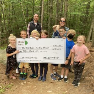 Children pose with large facsimile of a check donated to support programs.