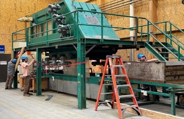 Workers install large fiber processing equipment