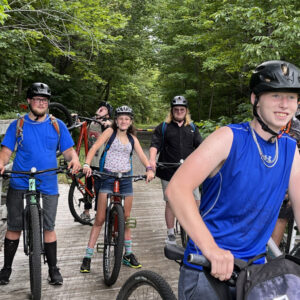 Teenagers on mountain bikes in woods.