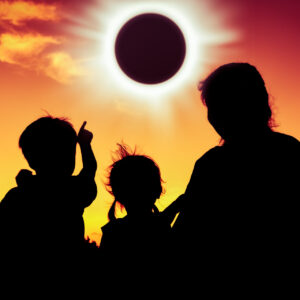 Silhouette of family watching solar eclipse.