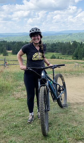 Women with mountain bike outside wearing Ride With Gratitude t-shirt