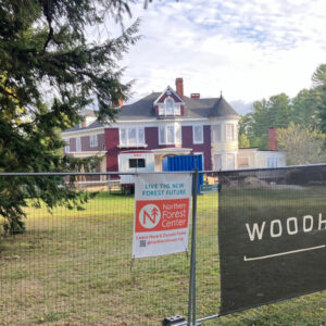 The historic Gehring House in Bethel, Maine, viewed behind a construction fence with signs.