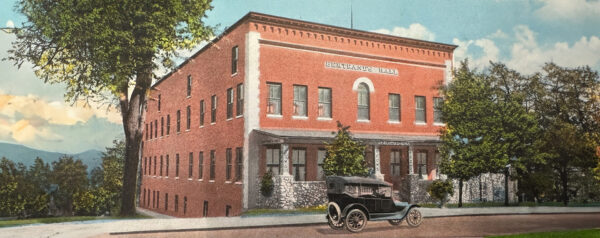 Picture of red brick building and Model T in rural setting in early 1900s.