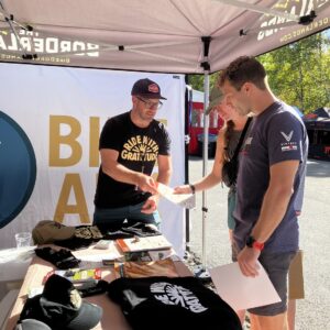 Man hands out literature at information booth at mountain biking event.