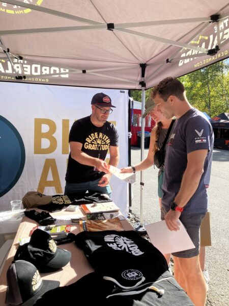 Man hands out literature at information booth at mountain biking event.
