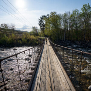 Man runs across river on walking bridge.