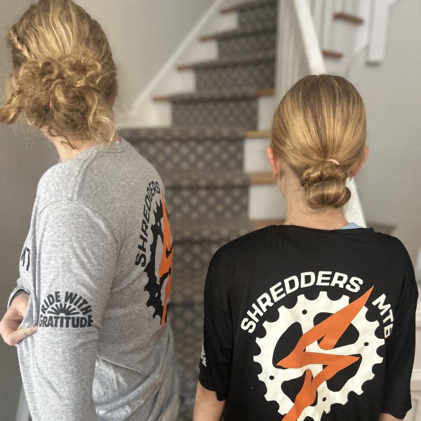 Girls modeling shirts that say Saratoga Shredders and Ride With Gratitude