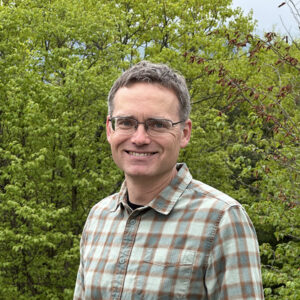 man smiling in front of trees