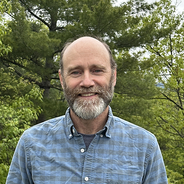 man smiling in front of trees