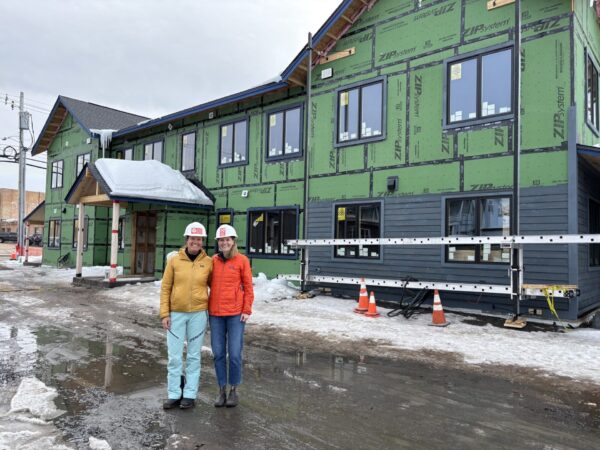 Two people stand in front of an apartment building under construction. 