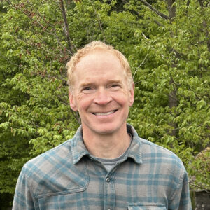man smiling in front of trees