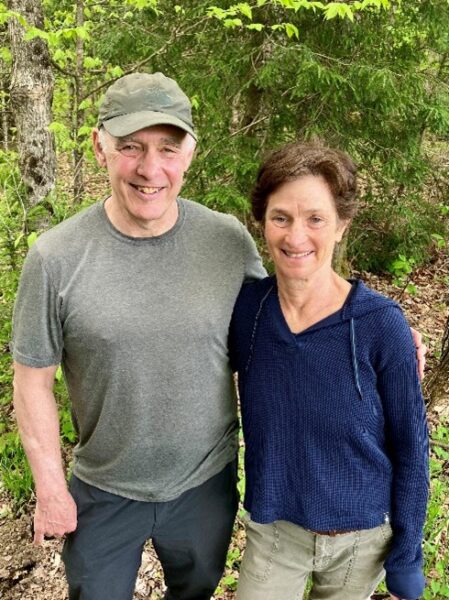 Man and woman standing at the edge of the woods.