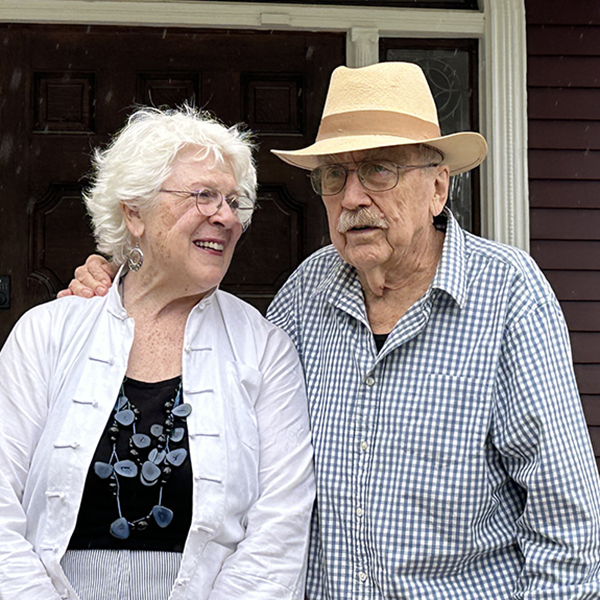 White haired woman looks affectionately at her husband.