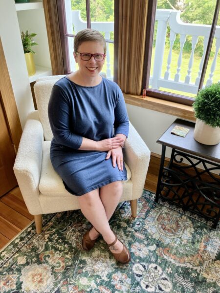 woman sits in chair by window in her apartment