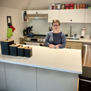 woman stands behind kitchen counter in her new apartment