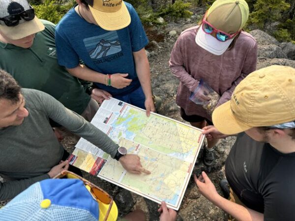 People stand in a circle and look at a trail map.