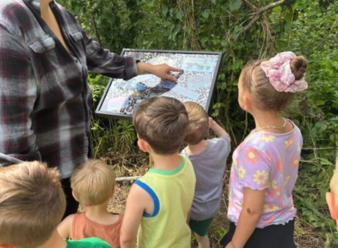 children look at story book displays on outdoor walk