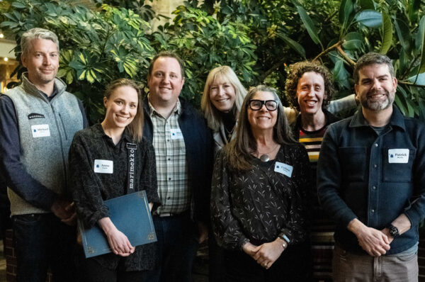 Group of men and women standing in front of indoor plants